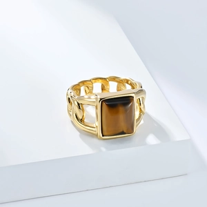 Détail d'une bague chaîne gourmette dorée avec une pierre œil de tigre sertie