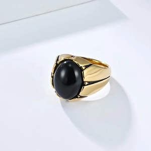 Detalle de anillo vintage de acero dorado con piedra negra ovalada y banda facetada