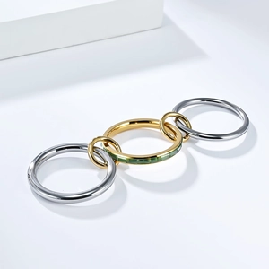 Detalle de anillo de triple banda entrelazada con gema verde y chapado en oro