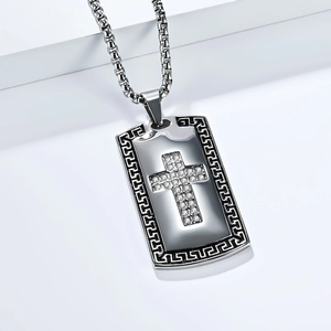 Close-up of vintage stainless steel cross pendant with Greek key pattern and white zircons