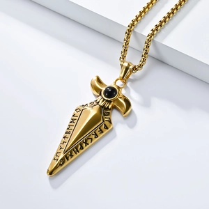 Macro side view of golden Viking spearhead pendant with black bead and rune carvings