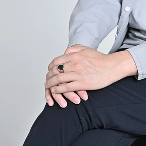 Detail van zilveren roestvrijstalen ring met vierkante zwarte steen om de vinger