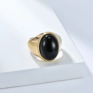 Gros plan d'une bague en acier inoxydable doré ornée d'une large gemme noire ovale
