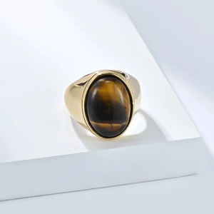 Détail d'une bague polie plaquée or avec un œil de tigre ovale sur un présentoir blanc