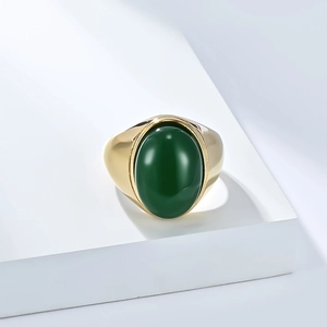 Détail d'une bague large en acier doré sertie d'une pierre ovale verte lisse et polie