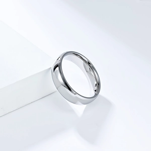 Gros plan d'une bague minimaliste en acier titane poli miroir sur un support blanc