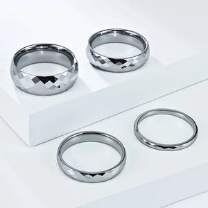 Detailed view of silver tungsten rings featuring geometric diamond cut surfaces in four widths