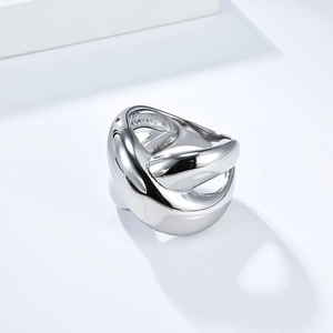 Macro detail of sculptural silver cross-over ring with polished thick metallic finish