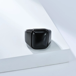 Macro-opname van gepolijste zwarte ring op wit platform met elegante schaduwen