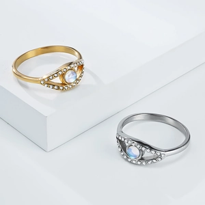 Polished moonstone evil eye rings in gold and silver finish on white geometric display
