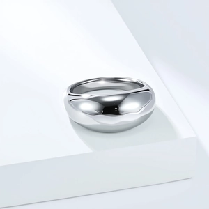 Minimalist wide dome ring in polished stainless steel with mirror finish on white pedestal