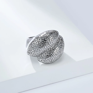 Macro detail of silver-tone ring featuring a unique textured surface and industrial design