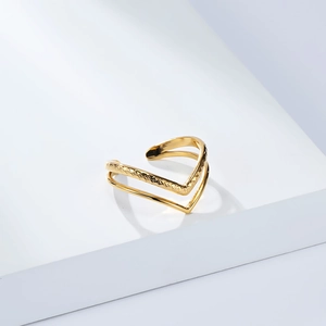 Minimalist double V-shaped gold plated ring with geometric pattern on a white platform