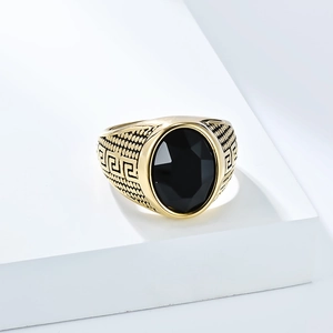 Makroaufnahme eines Herrenrings in Gold mit schwarzem Edelstein und griechischem Muster