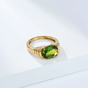 Détail d'une bague vintage dorée avec une grande pierre verte ovale et une texture côtelée