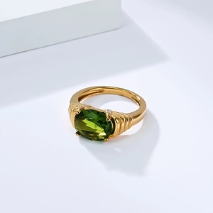Gros plan sur une bague plaquée or 18K avec grand gemme vert ovale et anneau texturé