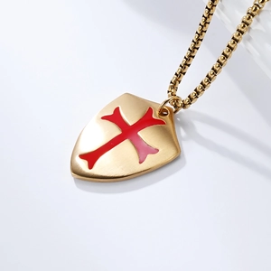 Close-up of golden shield pendant with red cross inlay on a matte stainless steel box chain