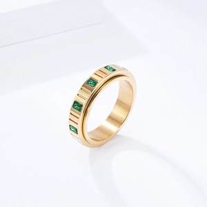 Detail eines drehbaren Goldrings mit smaragdgrünen Zirkonen und Streifentextur