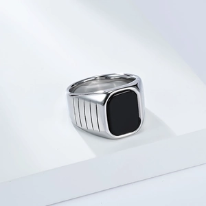 Gros plan d'une bague chevalière en acier titane avec pierre onyx noire et gravures