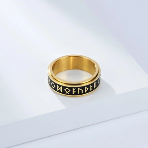 Detalle macro de un anillo vikingo dorado con símbolos rúnicos blancos sobre esmalte negro