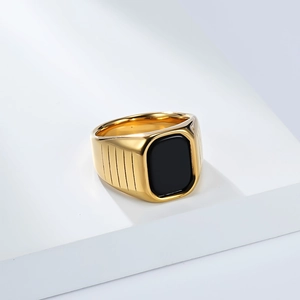 Vue macro d'une bague chevalière dorée avec pierre noire et texture à lignes verticales