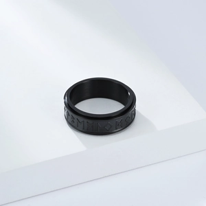 Detalle de anillo giratorio de acero negro mate con símbolos de runas nórdicas
