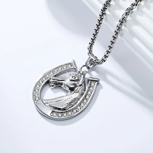 Macro detail of silver horseshoe and horse head pendant with sparkling crystal inlay