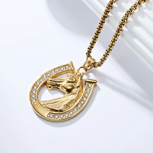 Detailed macro view of a golden horseshoe pendant with a realistic horse head and crystals