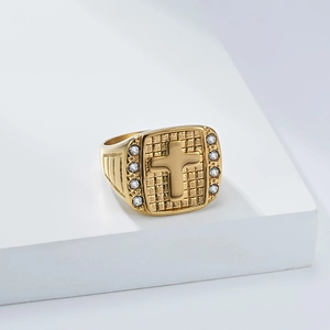 Detail eines Goldrings mit Kreuz und weißen Zirkonia auf quadratischem Netz-Hintergrund