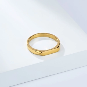 Bague géométrique dorée polie sur support blanc pour un look moderne et minimaliste chic