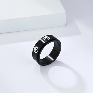 Detail of matte black titanium steel ring featuring Tai Chi Yin Yang patterns on white stand