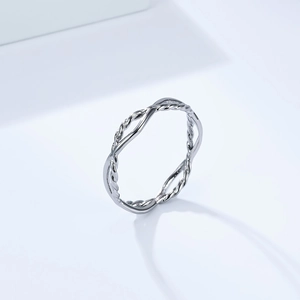 Macro detail of silver geometric twisted stainless steel ring on a minimal blue background
