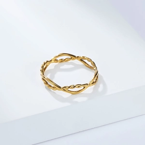 Golden stainless steel geometric twisted ring with a minimalist woven design on a white base