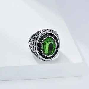 Macro detail of men's vintage steel ring featuring green oval gemstone and carving