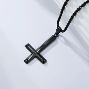 Close-up of black inverted cross pendant in polished stainless steel with pearl chain