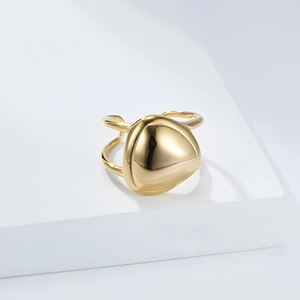 Detail of a minimalist gold-plated wide geometric triangular ring on a white pedestal