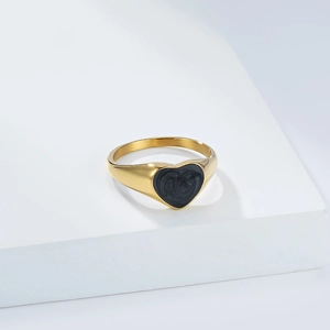 Detalle de anillo de corazón dorado con textura espiral de esmalte negro en escalones