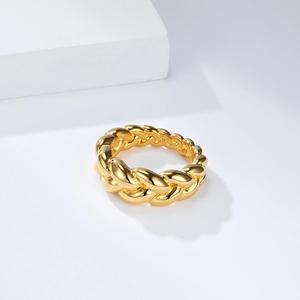 Detail of a golden twisted rope ring with high-polished metallic finish on a minimalist base