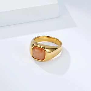 Macro shot of gold stainless steel ring with square orange cat eye stone in a white scene