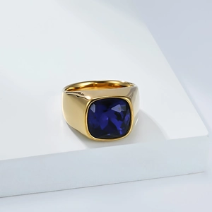 Détail de la bague chevalière dorée polie ornée d'une pierre précieuse carrée bleu marine