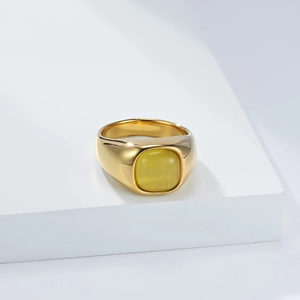 Macro detail of a wide gold stainless steel ring with a square yellow cat eye stone inlay
