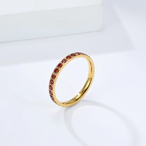 Dettaglio ravvicinato di un anello eternity dorato con micro-pavé di gemme rosse brillanti