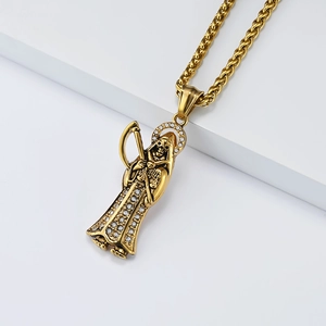 Macro shot of gold Santa Muerte reaper pendant with white crystal details on wheat chain