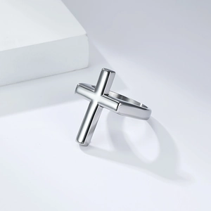 Gros plan d'une bague croix en acier inoxydable poli sur support géométrique blanc