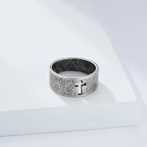Detailed view of vintage steel ring featuring a hollow cross design on a white platform
