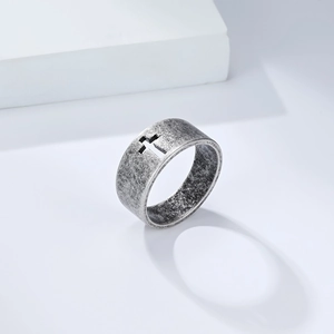 Detail of vintage wide stainless steel ring featuring a cutout cross and aged silver finish
