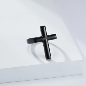 Gros plan d'une bague croix noire avec finition polie sur un présentoir blanc