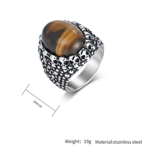 Detailed macro view of punk skull carvings and brown tiger eye stone on stainless steel ring
