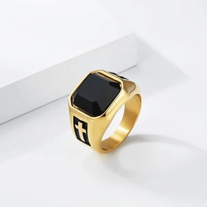 Detail of gold signet ring featuring a black gemstone and hollow cross side engraving
