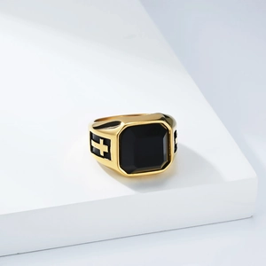 Macro shot of gold signet ring with square black stone and cross relief detail